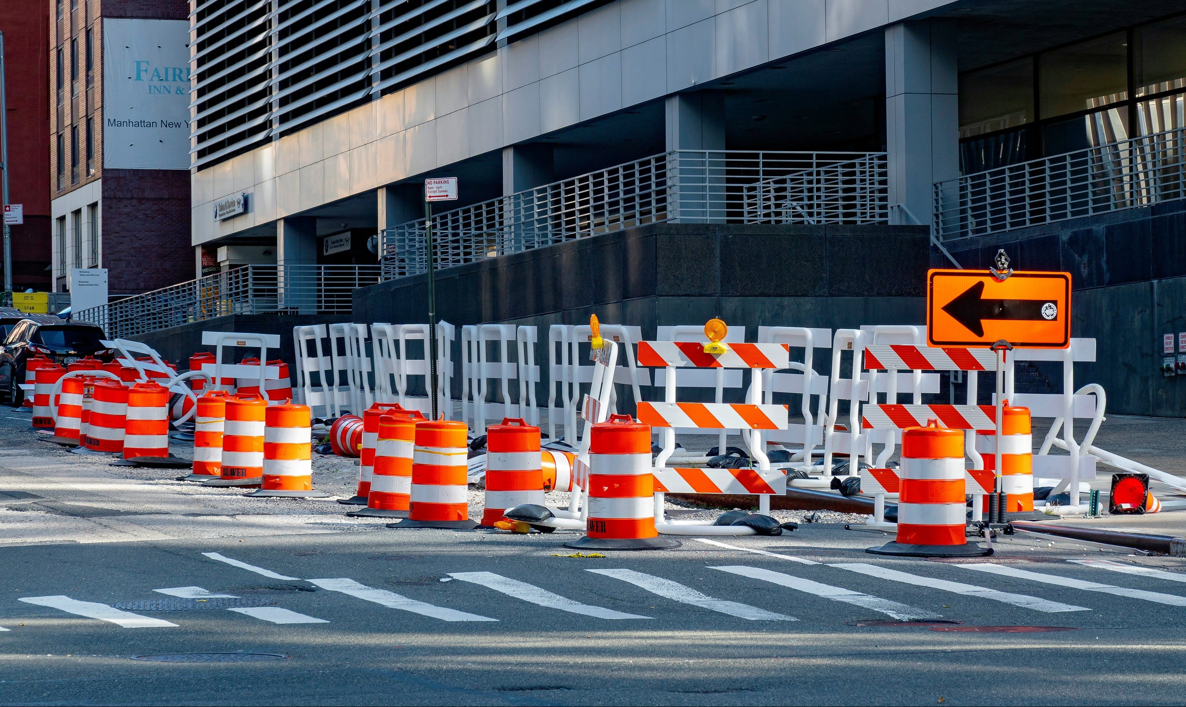 Construction cones and barriers blocking a street with a building in the background
